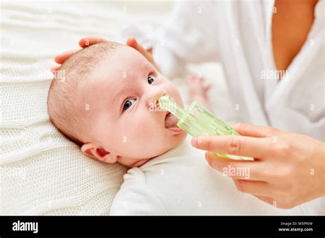 Bambino con raffreddore che viene trattato con aspiratore nasale