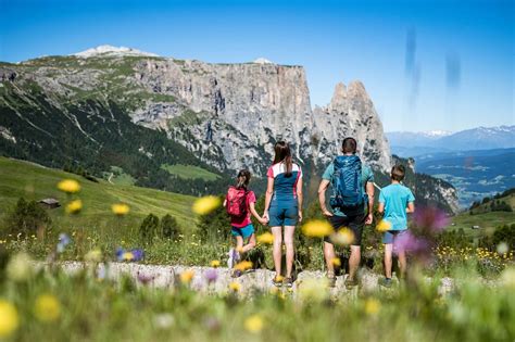 Famiglia con bambini che passeggia su un sentiero fiorito sull'Alpe di Siusi