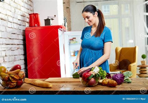 Immagine di una donna incinta che prepara cibo in cucina