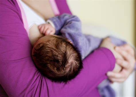 Neonato che viene allattato al seno