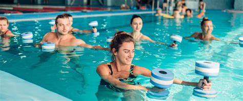 Donna incinta che esegue esercizi di acquagym con un tubo galleggiante