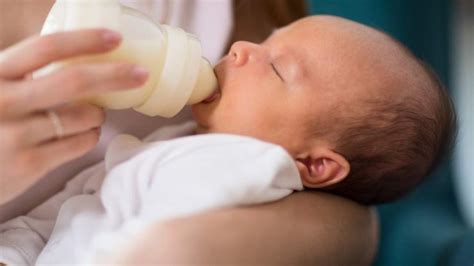 neonato in posizione semi-eretta mentre beve dal biberon