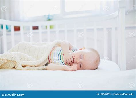 Bambino che dorme in una culla con corredino