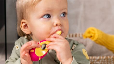 Bambino che morde un anello per la dentizione