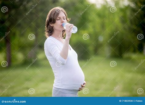 Donna incinta che beve acqua e mangia frutta
