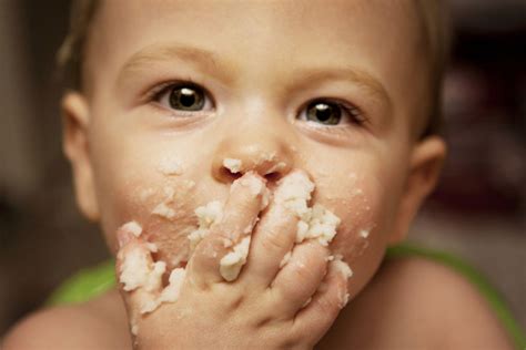 Un bambino che mangia con le mani piccoli pezzi di cibo