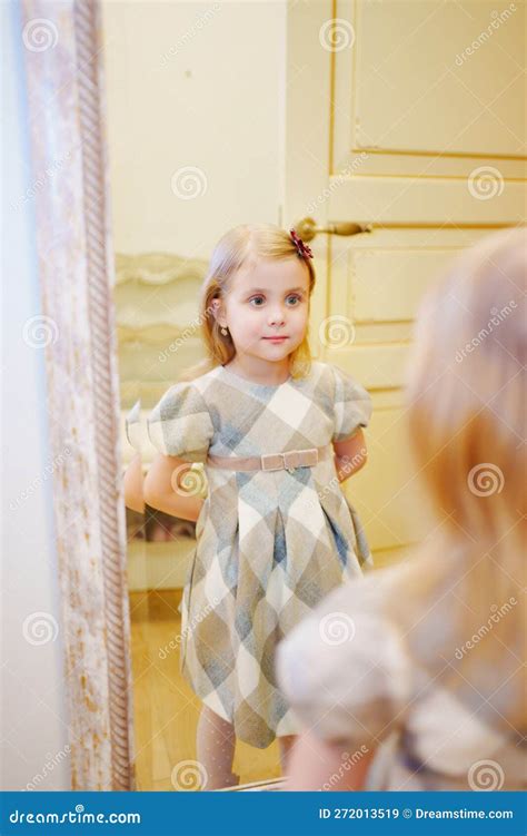 Bambina che si guarda allo specchio con un vestito nuovo