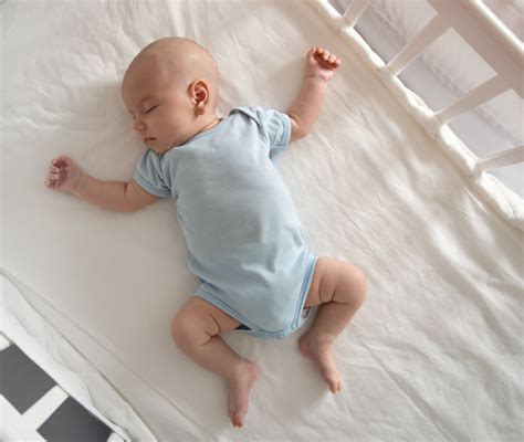 Neonato che dorme in una culla con vestiti per neonati morbidi