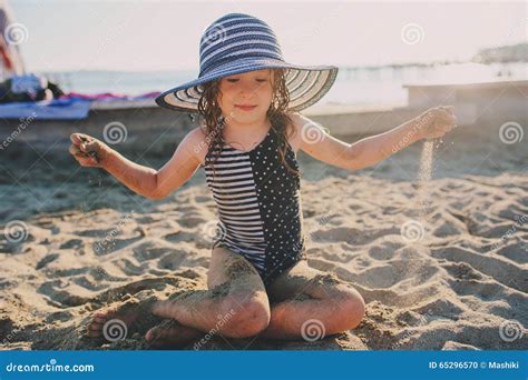 Bambino che gioca in spiaggia con costume da bagno e cappellino