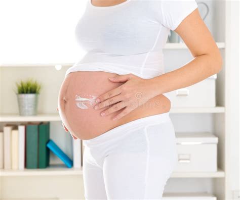 Donna incinta che massaggia la crema sulla pancia