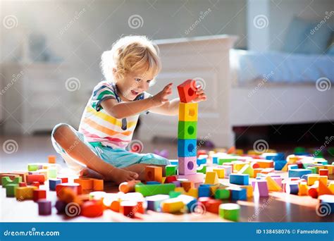 bambino che gioca con giocattoli indossando una tuta adidas colorata