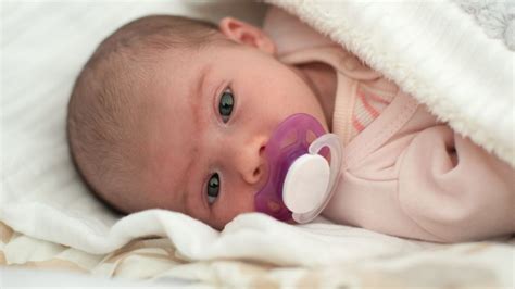 Un neonato che dorme serenamente con un ciuccio in silicone