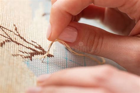 Mani che ricamano un motivo floreale su un tessuto