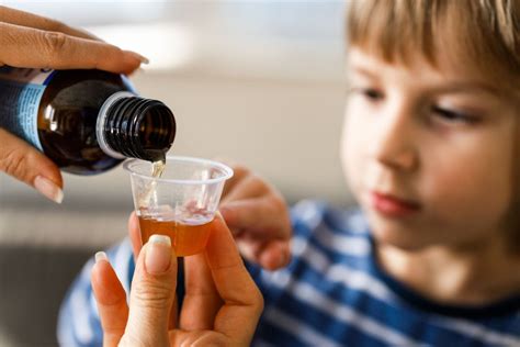 Bambino che prende uno sciroppo per la febbre