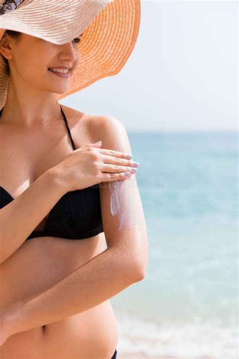 Donna incinta che si protegge dal sole con un cappello e crema solare