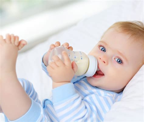 Bambino che beve latte dal biberon con mamma