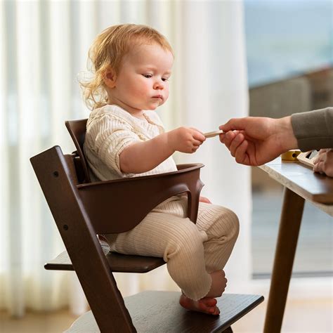 Bambino seduto sul seggiolone Stokke Tripp Trapp con cuscini