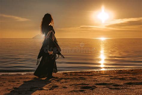 Donna incinta che cammina su una spiaggia al tramonto